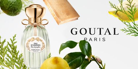 El frasco del perfume Eau d'Hadrien de Goutal Paris está rodeado de cítricos y hojas verdes que resaltan sobre un fondo claro. El logo de Goutal Paris está visiblemente colocado junto al frasco.