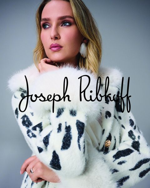 Una mujer con un abrigo de piel sintética blanca con lunares negros posa pensativa. El nombre "Joseph Ribkoff" está escrito en letras negras sobre la imagen.