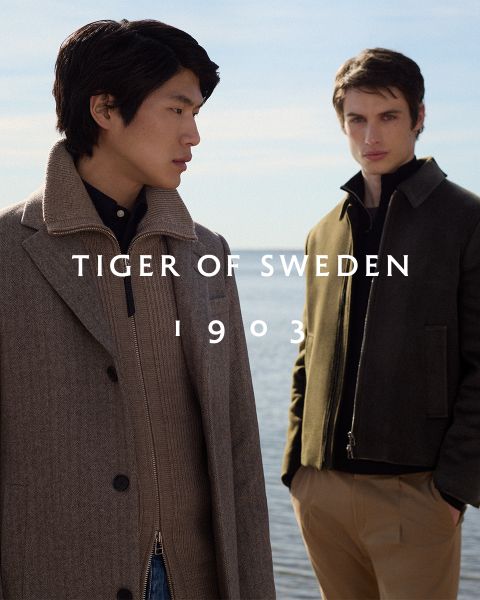 Dos hombres con abrigos elegantes están de pie al aire libre junto al agua bajo un cielo despejado. El texto "TIGER OF SWEDEN 1903" aparece en el centro de la imagen.