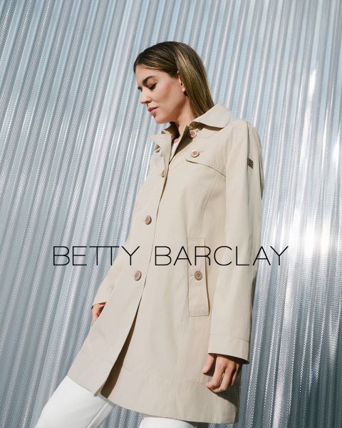 Una mujer con una gabardina beige está de pie frente a un fondo metálico ondulado. El abrigo tiene botones grandes y un cuello. El texto "Betty Barclay" está superpuesto a la imagen. Parece satisfecha y mira hacia la derecha.