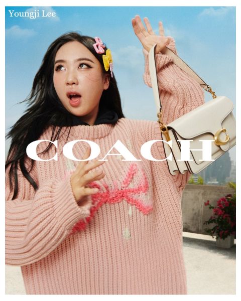 Una persona sostiene un bolso blanco y lleva un jersey de punto rosa y un adorno para el pelo. En el fondo se ven un cielo azul y un paisaje de tejados. El texto en la imagen dice "Youngji Lee" y "Coach".