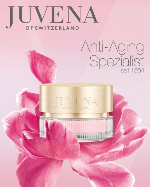 Frente a una gran flor rosa hay un recipiente de crema antiedad de Juvena of Switzerland. El fondo es un degradado de rosa y blanco. El texto dice: "Juvena of Switzerland, especialista antiedad desde 1954".