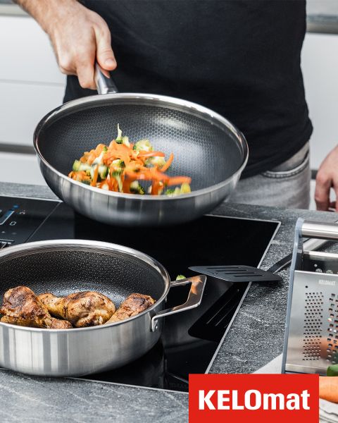 Una persona fríe verduras en una sartén sobre una estufa, mientras que cerca hay otra sartén con pollo cocido. En la esquina se ve el logo de KELOmat.