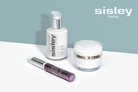 Una colección de productos para el cuidado de la piel de Sisley Paris sobre una superficie clara. Incluye un frasco con bomba que dice "Emulsion écologique", un pequeño tubo morado y un recipiente blanco con tapa metálica. El logotipo de la marca se muestra en la esquina superior derecha.
