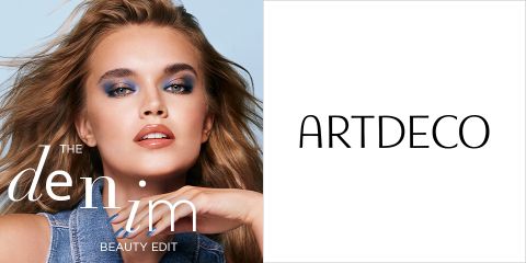 Una modelo con cabello largo y un llamativo maquillaje de ojos azul posa con un conjunto de mezclilla. A la izquierda está el texto "THE DENIM BEAUTY EDIT". A la derecha está el nombre de la marca "ARTDECO" sobre un fondo blanco.