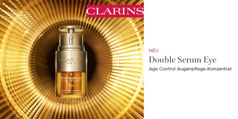Centrada en un brillante fondo dorado, se encuentra el frasco dorado de Clarins Double Serum Eye. El texto a la derecha dice "NUEVO Double Serum Eye Concentrado Contorno de Ojos Antiedad". En la parte superior de la imagen se ve un logotipo de Clarins.