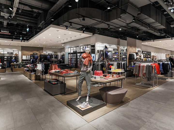 Una tienda de ropa moderna con elegantes maniquíes que exhiben ropa de mujer. La tienda cuenta con estantes y expositores bien organizados con una variedad de prendas y accesorios, y una iluminación brillante realza el espacio.