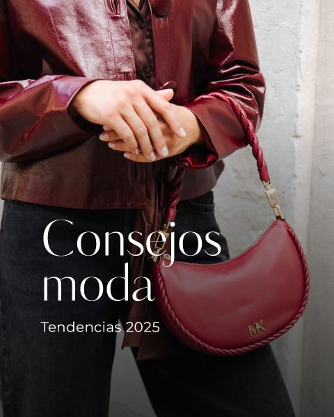 Una persona con una brillante chaqueta de cuero color burdeos sostiene un bolso de mano color burdeos a juego con el logo de MK. El texto en la imagen dice: "Consejos moda. Tendencias 2025.