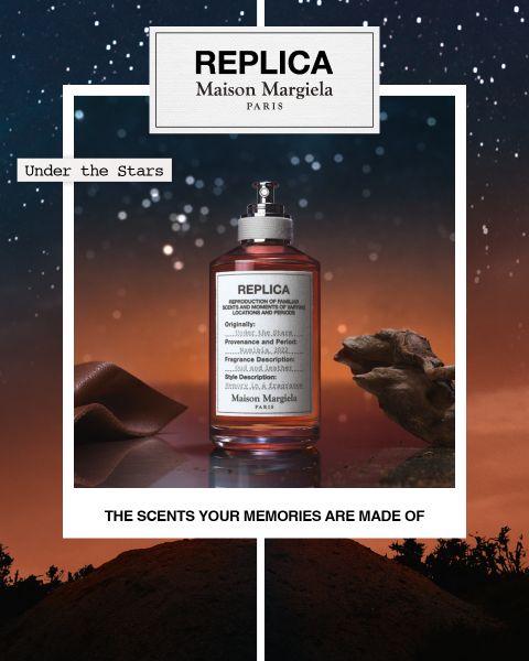 Un frasco del perfume "Replica Maison Margiela" con la inscripción "Under the Stars" se encuentra frente a un cielo estrellado con terreno rocoso. El texto en la parte inferior dice: "Las fragancias de las que están hechos tus recuerdos".