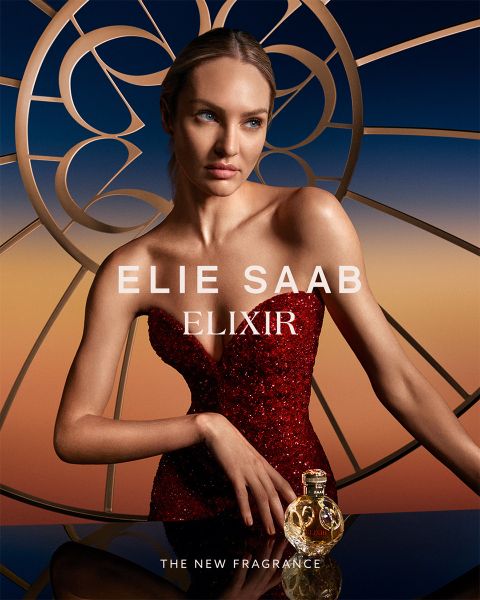 Persona con un vestido rojo de lentejuelas posa con el perfume Elie Saab Elixir. El fondo muestra un diseño circular estilizado con un degradado de color de naranja a azul. El texto dice: "Elie Saab Elixir" y "La nueva fragancia".