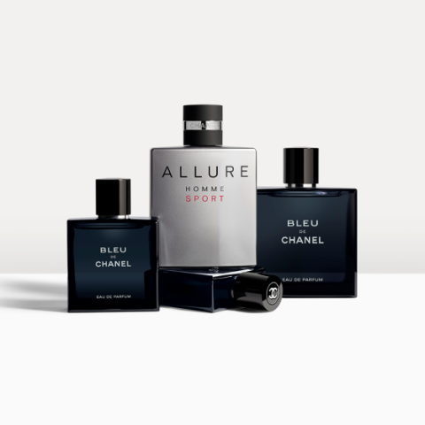 Se exhiben tres frascos de perfume. En el centro, un frasco grande de "Allure Homme Sport" de Chanel, flanqueado por dos frascos de "Bleu de Chanel". Los frascos están elegantemente dispuestos sobre un fondo neutro.