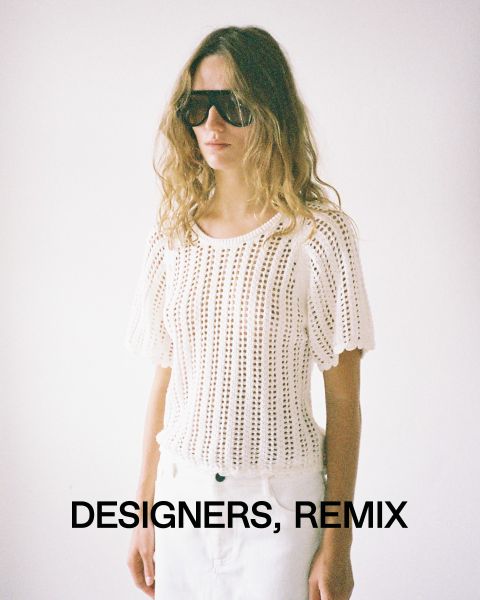 Una persona con pelo largo, gafas de sol grandes y un top blanco de ganchillo está de pie frente a un fondo sencillo. En la parte inferior de la imagen se lee "Designers, Remix".