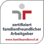 Logotipo con un símbolo estilizado con elementos grises y rojos. El texto dice "empleador certificado como familiarmente amigable", en la parte inferior está el sitio web "www.familieundberuf.at".