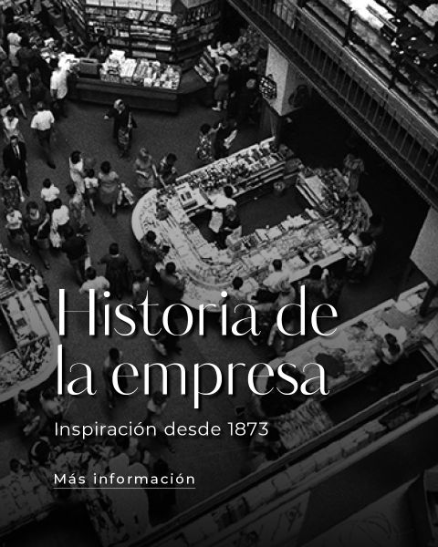 Foto en blanco y negro de un mercado bullicioso con gente caminando entre los puestos. El texto superpuesto en español dice: "Historia de la empresa. Inspiración desde 1873. Más información.