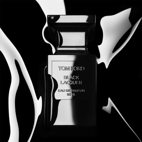 Un elegante frasco de perfume negro con la inscripción "Tom Ford Black Lacquer Eau de Parfum 50 ml" se encuentra frente a un fondo contrastante en blanco y negro similar a un líquido, lo que le da un aspecto lujoso y elegante.