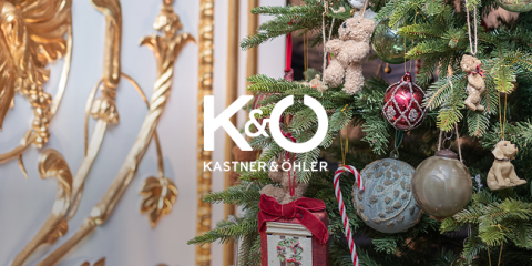 Nahaufnahme eines geschmückten Weihnachtsbaums mit verschiedenen Ornamenten, darunter Zuckerstangen und Kugeln, vor einem glänzenden goldenen Hintergrund. Das Logo „Kastner & Öhler“ ist prominent über dem Bild platziert.