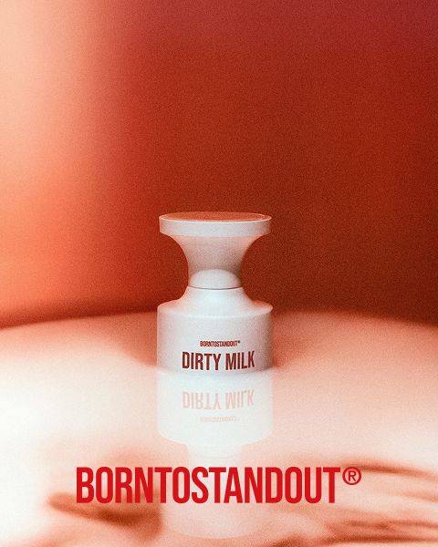 Una botella blanca con la inscripción "DIRTY MILK" se encuentra sobre una superficie reflectante con un cálido degradado rojo. Debajo, en negrita y en rojo, se lee "BORNTOSTANDOUT®".
