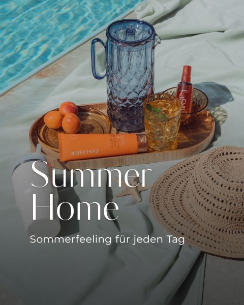 Una escena en la piscina con un sombrero de paja, protector solar, albaricoques, una jarra de cristal, bebidas y una bandeja. El texto dice: "Summer Home - Sensación de verano para cada día.