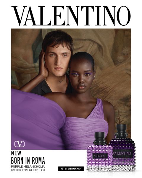 Un hombre y una mujer posan juntos en escalones de piedra. El hombre lleva un abrigo negro, la mujer un llamativo conjunto rosa con los hombros descubiertos. En la parte inferior derecha se ven dos frascos de perfume de Valentino. Encima pone "VALENTINO".