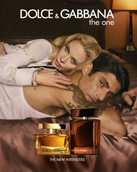 Un hombre sin camisa y una mujer en bikini blanco yacen sobre un flotador blanco cerca de agua azul rocosa. En primer plano hay dos frascos de perfume azul claro de Dolce & Gabbana. El texto dice "Dolce & Gabbana Light Blue".