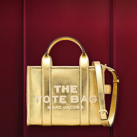 Un bolso estructurado de metal con asas sobre un fondo burdeos. Encima está la palabra "BOLSO DE LOS DESEOS".