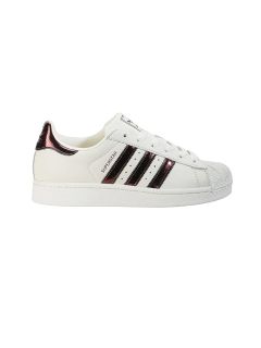 Zapatilla blanca con rayas Adidas negras y contornos abstractos de estrellas negras en los laterales; estilo de caña baja con puntera texturizada.