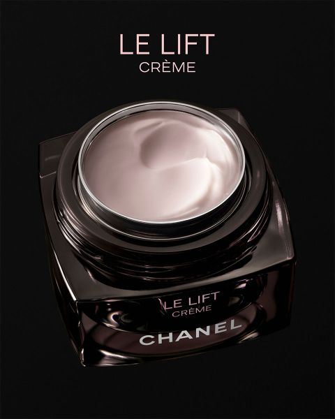 Una mujer con piel radiante posa junto a dos productos de corrector Chanel Les Beiges y lleva joyas de plata sobre un fondo beige suave.