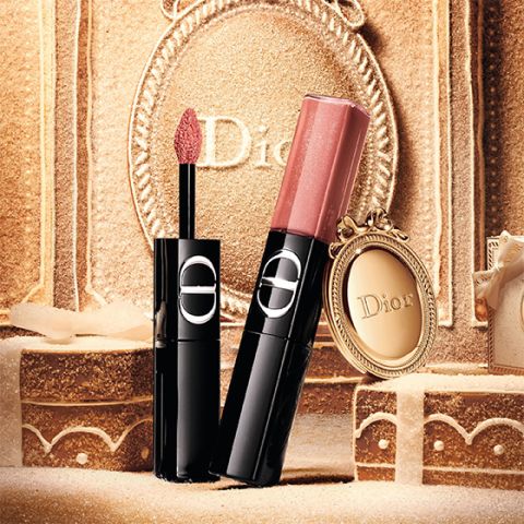 Un labial líquido rojo de Dior, con el aplicador extraído y la tapa plateada a un lado, todo sobre un fondo blanco.