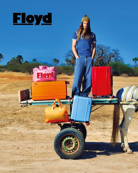 Un SUV clásico de diseño retro con equipaje en el techo está estacionado frente a un fondo blanco. Encima del vehículo, la palabra "Floyd" destaca en negritas letras negras.