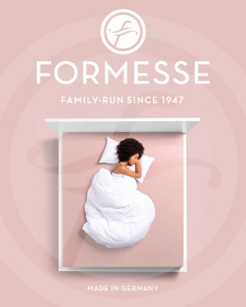 Una mujer con cabello rubio duerme de lado en una cama azul claro. Su cabeza descansa sobre una almohada blanca. En el borde inferior de la imagen se ve la inscripción "Formesse" y un logo.
