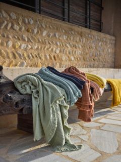 Cuatro cojines rectangulares de color verde oliva con un sutil borde de volantes están dispuestos en dos filas frente a un fondo con un degradado de color gris y blanco.