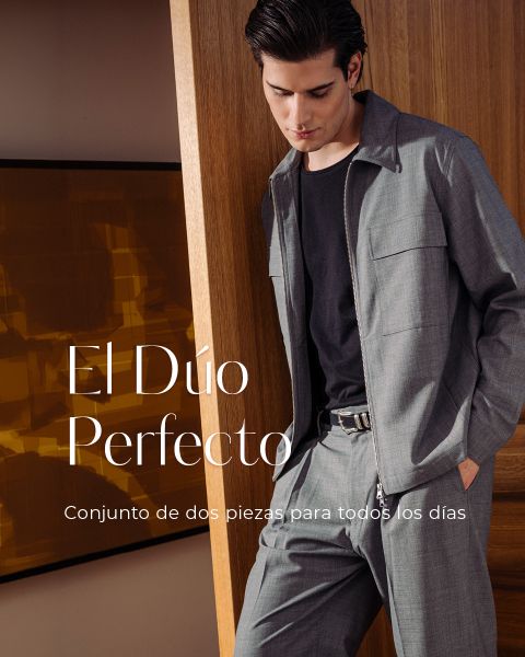 Un hombre con ropa de color beige claro está de pie sonriendo frente a unos ventanales. El texto en español dice: "El Dúo Perfecto. Conjunto de dos piezas para todos los días.".