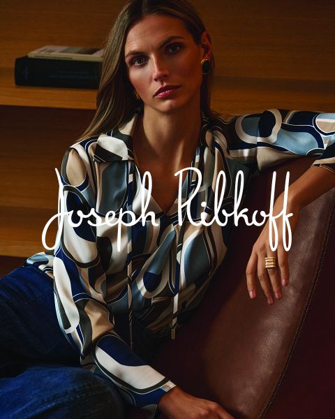 Una mujer con una blusa estampada y jeans está sentada en un sofá de cuero; sobre la imagen está escrito "Joseph Ribkoff" en letras blancas.