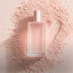 Un frasco de perfume de cristal transparente con un tapón de color rosa pálido se encuentra sobre polvos rosas, con una marca de verificación dibujada en el polvo a su lado.