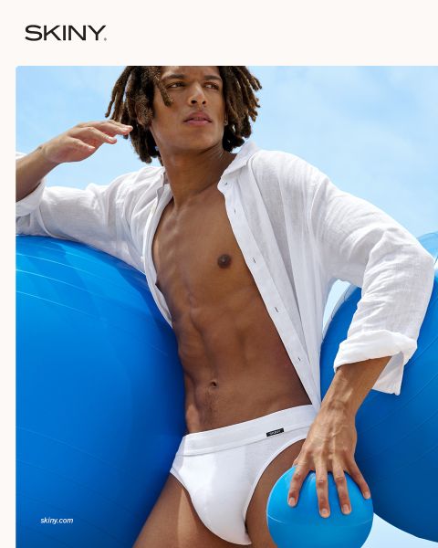 Un hombre musculoso y sencillo mira hacia abajo. Lleva un suéter rojo sobre el hombro y ropa interior verde. El fondo es de color rojo oscuro y la palabra "SKINY" aparece en la parte inferior.