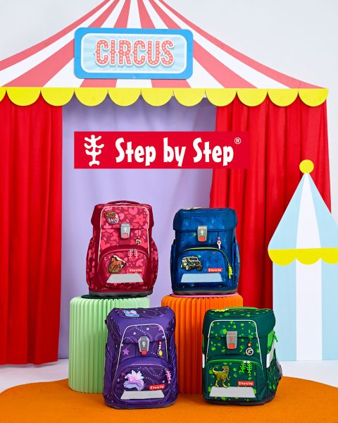 Dos niños están sentados en el suelo frente a una tienda de juegos, cada uno con una mochila colorida. A la izquierda está el texto "¡Siempre encaja garantizado!". En el fondo se ven estanterías con juguetes y decoración.