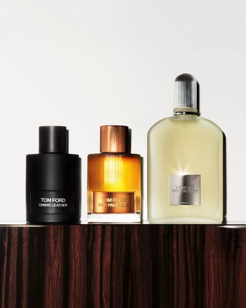 Una fotografía en blanco y negro que muestra a un hombre y una mujer con sombreros de ala ancha. Están de pie muy cerca uno del otro. En la esquina inferior izquierda hay una botella que dice "Tom Ford Eau d'Ombre Leather". El nombre de la marca es claramente visible.