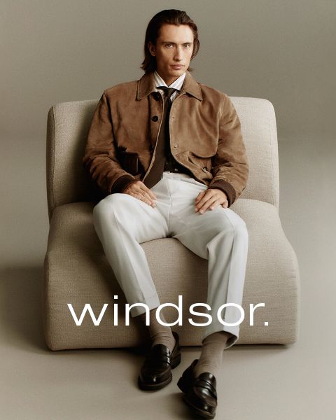 Un hombre con un abrigo marrón y una mujer con un abrigo y una bufanda color crema están de pie al aire libre con montañas al fondo. La palabra "windsor." se puede leer en la parte inferior de la imagen.