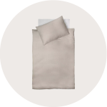 Draufsicht auf ein ordentlich gemachtes Bett mit einer hellbeigen Bettdecke und passenden Kissen auf weißem Hintergrund.