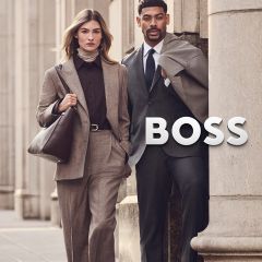 Una mujer con un traje beige y un hombre con un traje gris están de pie junto al logo de BOSS.