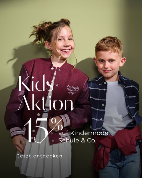 Dos niños están de pie sonriendo frente a una pared verde. La niña lleva una chaqueta deportiva marrón y el niño una camisa a cuadros. El texto sobre ellos dice: "Kids Aktion 15% de descuento en moda infantil, escuela & Co. Descúbrelo ahora".