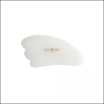 Ein weißes Gua Sha-Gesichtsmassagegerät aus Jade mit gezackten Rändern und dem Markennamen "Sentara" in Golddruck auf der Oberfläche, abgebildet auf einem schlichten weißen Hintergrund.