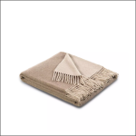 Eine gefaltete beigefarbene Decke mit ausgefransten Rändern, ordentlich auf einem weißen Hintergrund platziert.