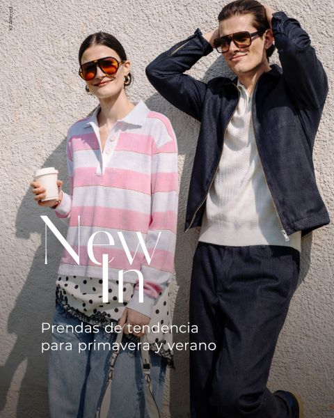 Dos personas elegantes con gafas de sol posan al aire libre; uno lleva una camisa de rayas rosas, el otro una chaqueta oscura. Texto: "New In. Prendas de tendencia para primavera y verano."