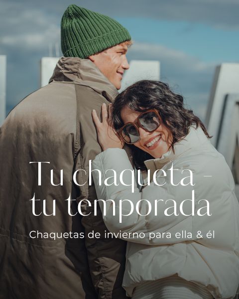 Una mujer sonriente con gafas de sol abraza a un hombre con un gorro verde y un abrigo de invierno. Ambos llevan chaquetas abrigadas. El texto superpuesto en español dice: "Tu chaqueta - tu temporada. Chaquetas de invierno para ella & él.