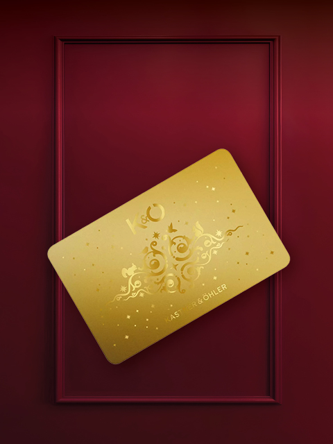 Una tarjeta dorada con un patrón ornamentado y las letras "K&O" está colocada en diagonal sobre un fondo burdeos con un marco rectangular.