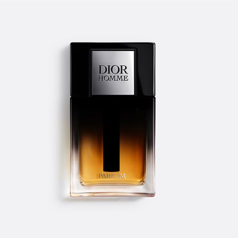 Un frasco de Dior Homme Parfum con un diseño de vidrio con degradado claro-oscuro y un tapón negro sobre un fondo blanco liso.
