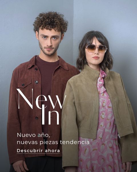 Un hombre y una mujer con atuendos elegantes posan frente a un fondo sencillo con texto que promociona las nuevas tendencias de moda para el nuevo año en español.