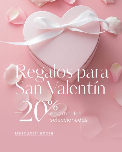 Caja de regalo rosa con forma de corazón con cinta blanca sobre fondo rosa, rodeada de pétalos de rosa. El texto en español ofrece un 20% de descuento en regalos seleccionados para el Día de San Valentín.
