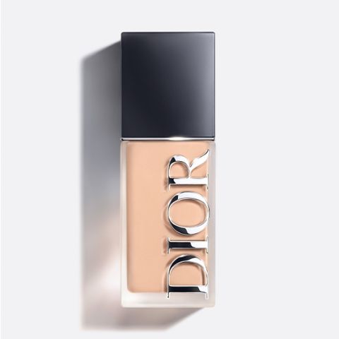 Una botella de base de maquillaje Dior con tapón negro y la inscripción "DIOR" verticalmente en la parte delantera, fotografiada sobre un fondo claro.